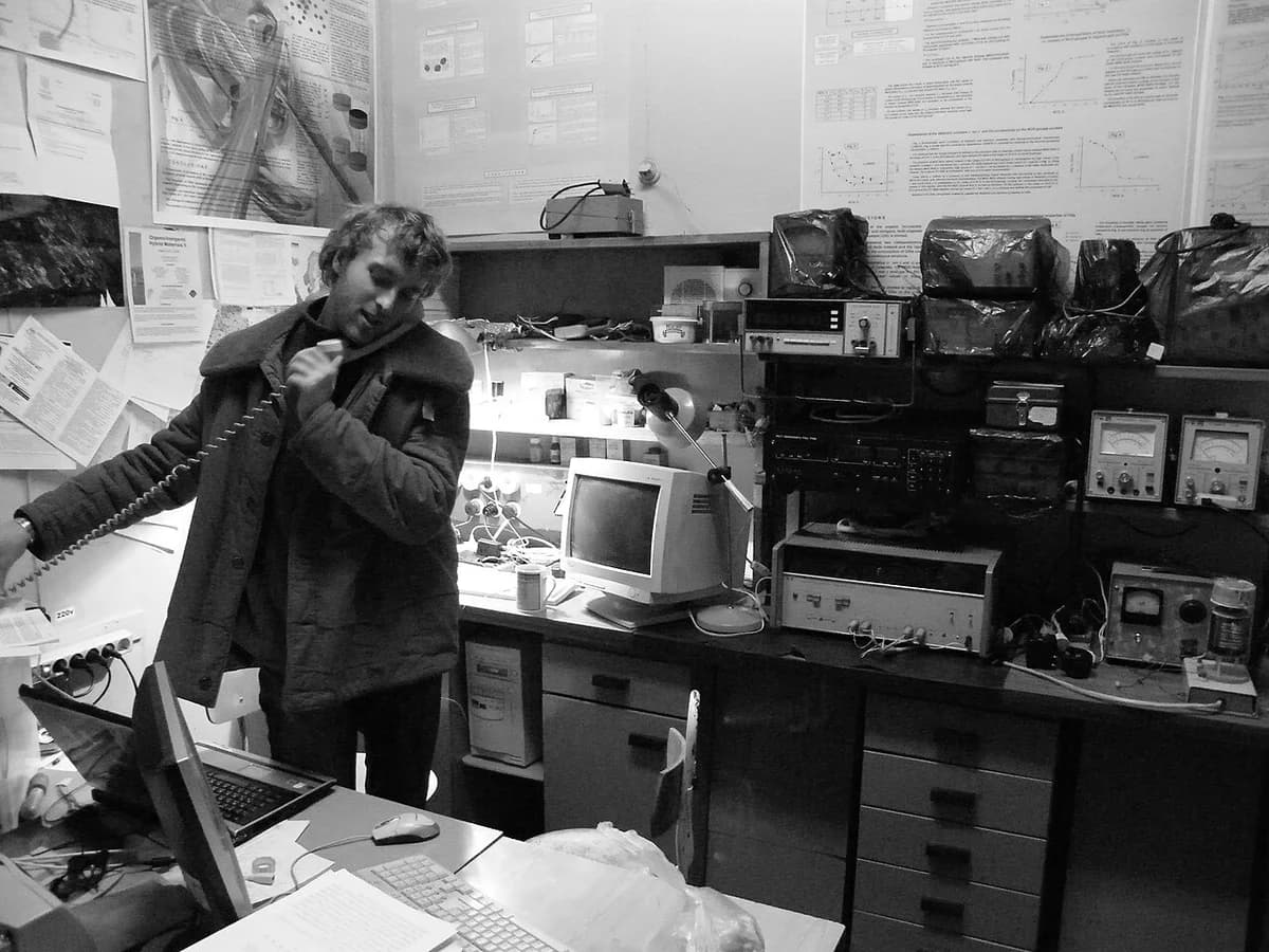 A young scientist using equipment in a cluttered laboratory at night.