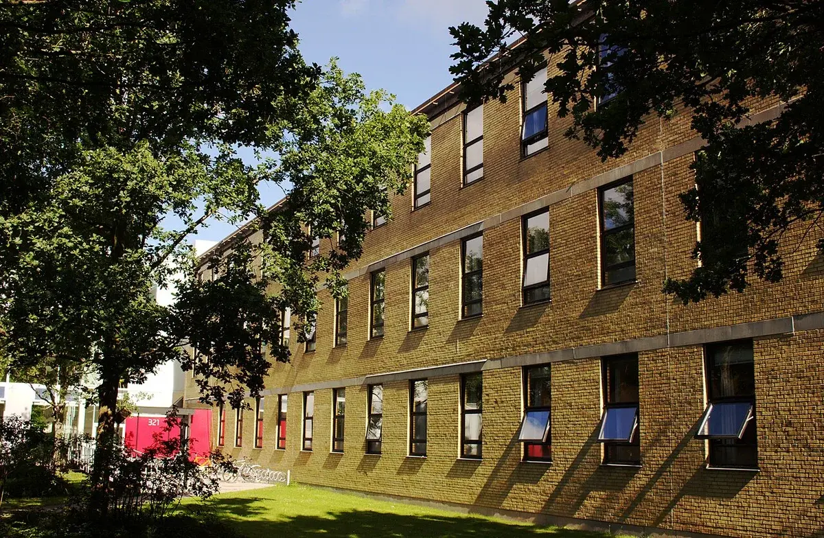 A DTU campus building marked 321, seen through trees, with another building behind it.