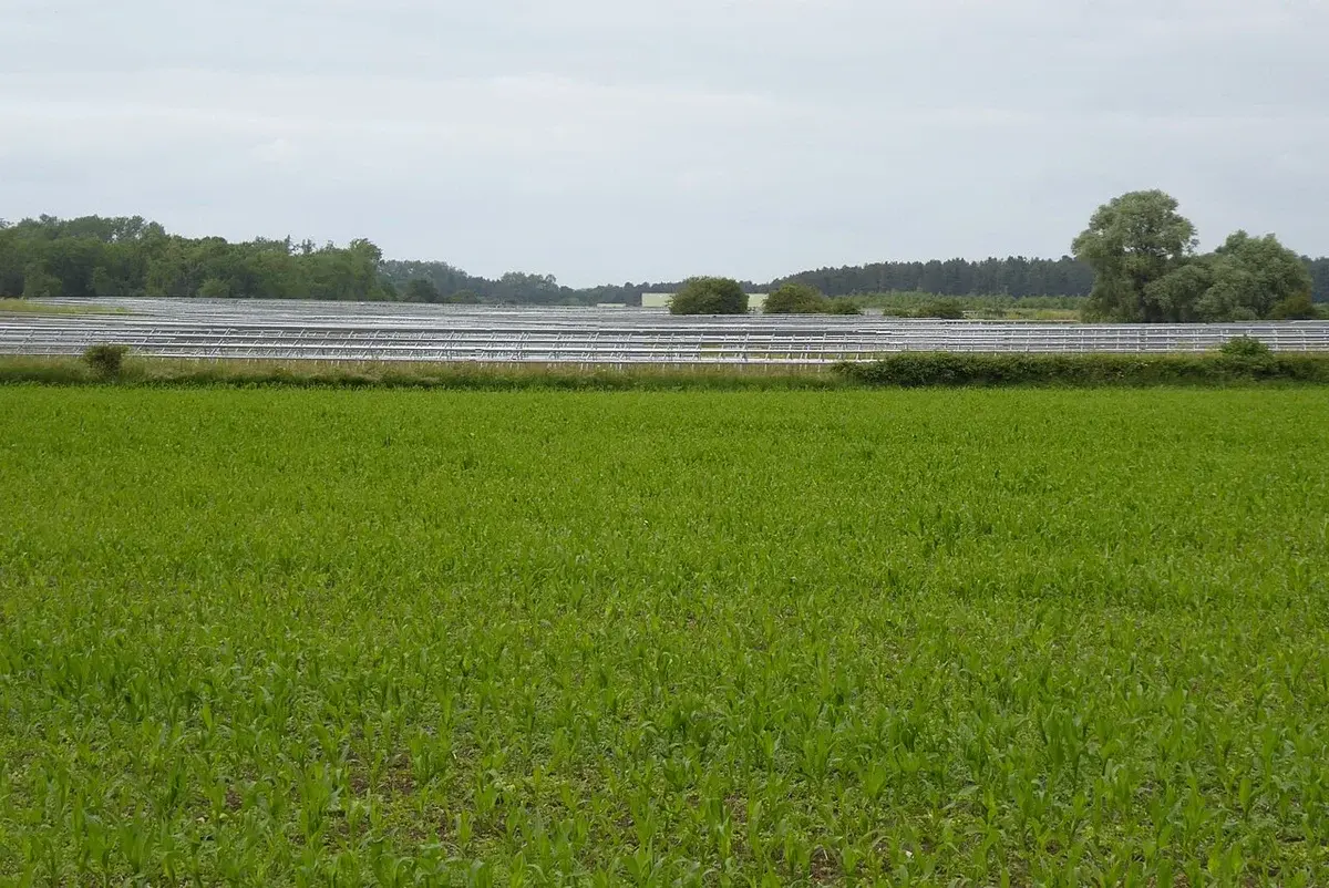 Rows of solar panel structures under construction in a rural field.
