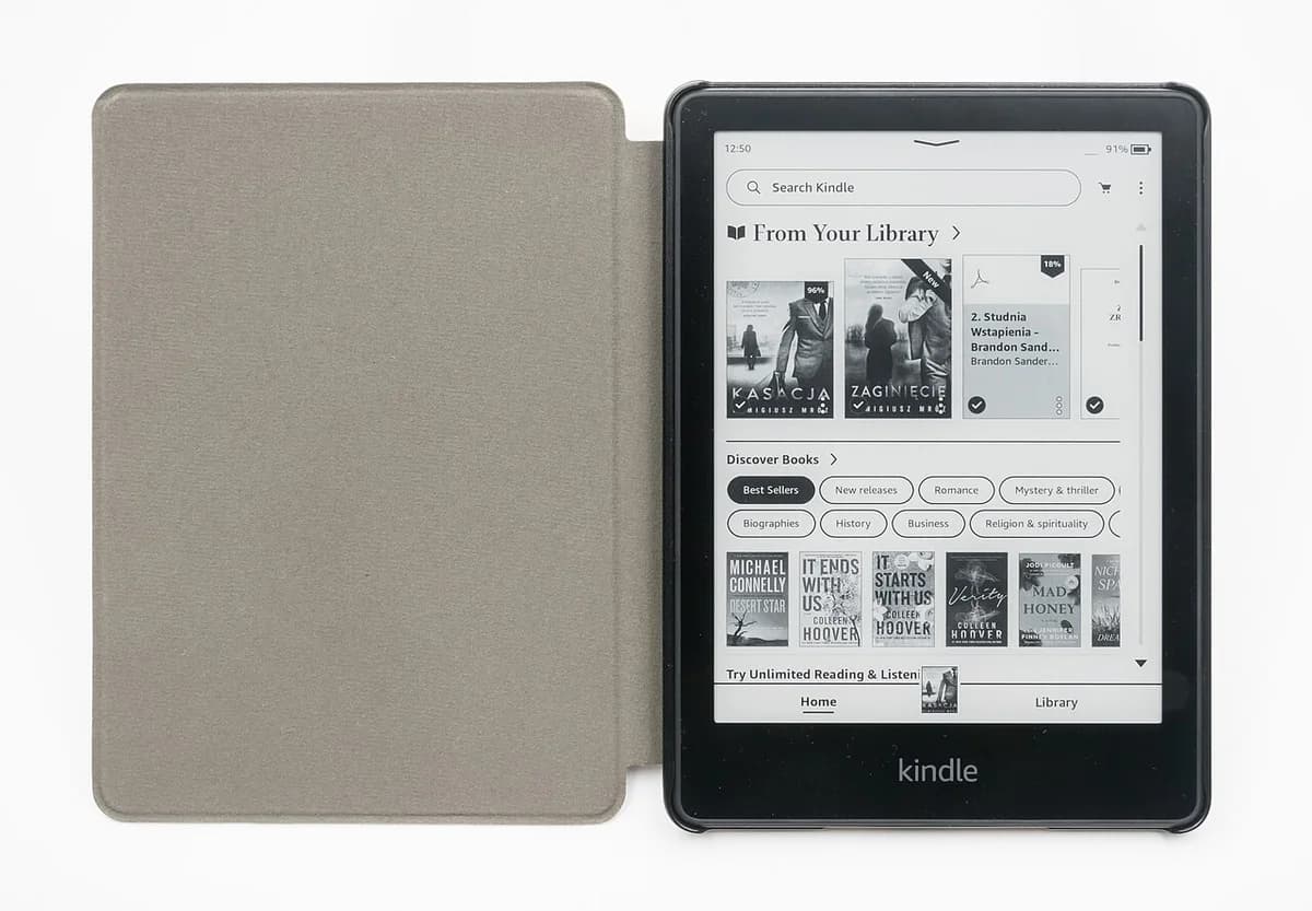 A Kindle Paperwhite e-reader in a gray cover with its screen on.