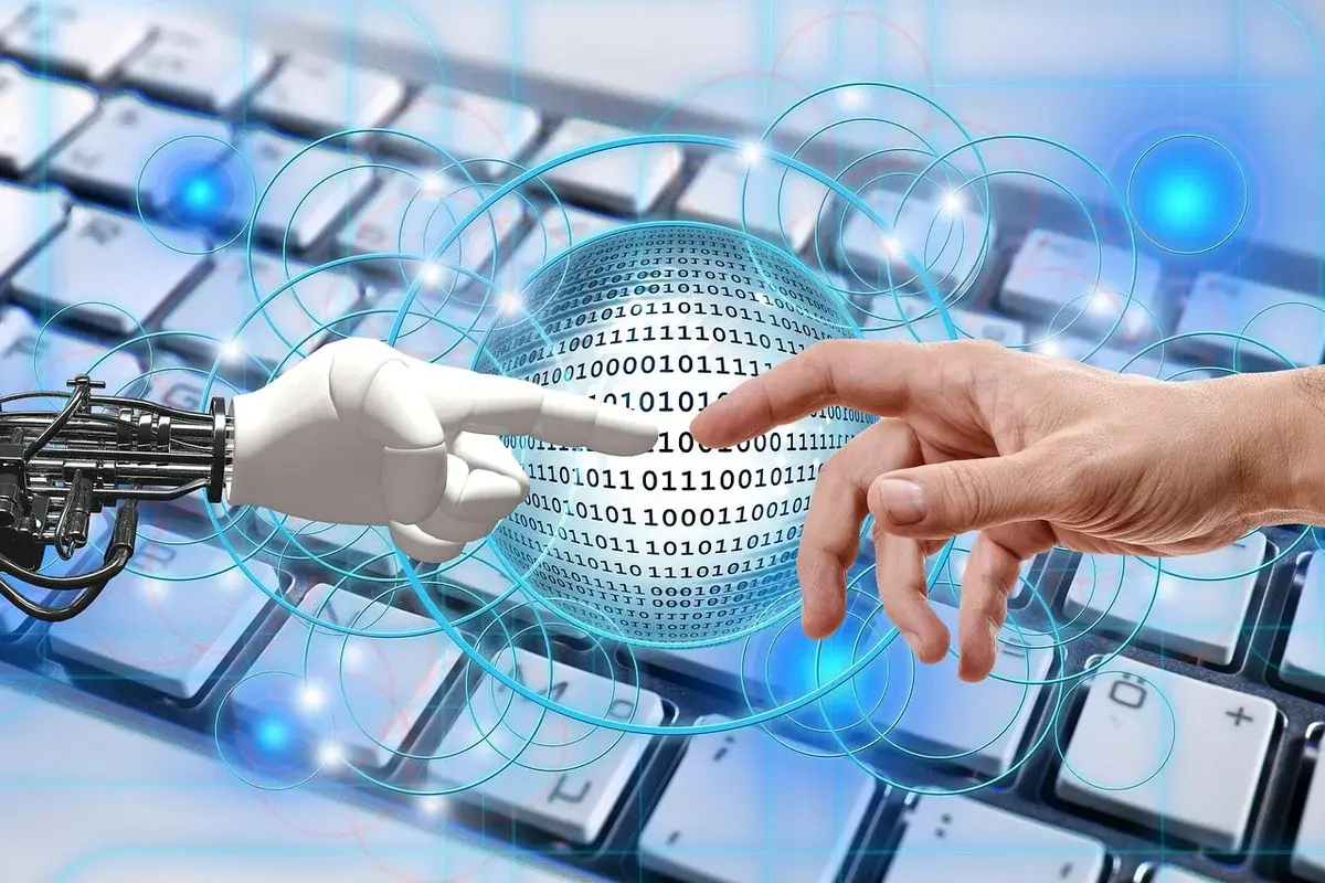 A human hand and a robot hand reaching toward each other over a keyboard.