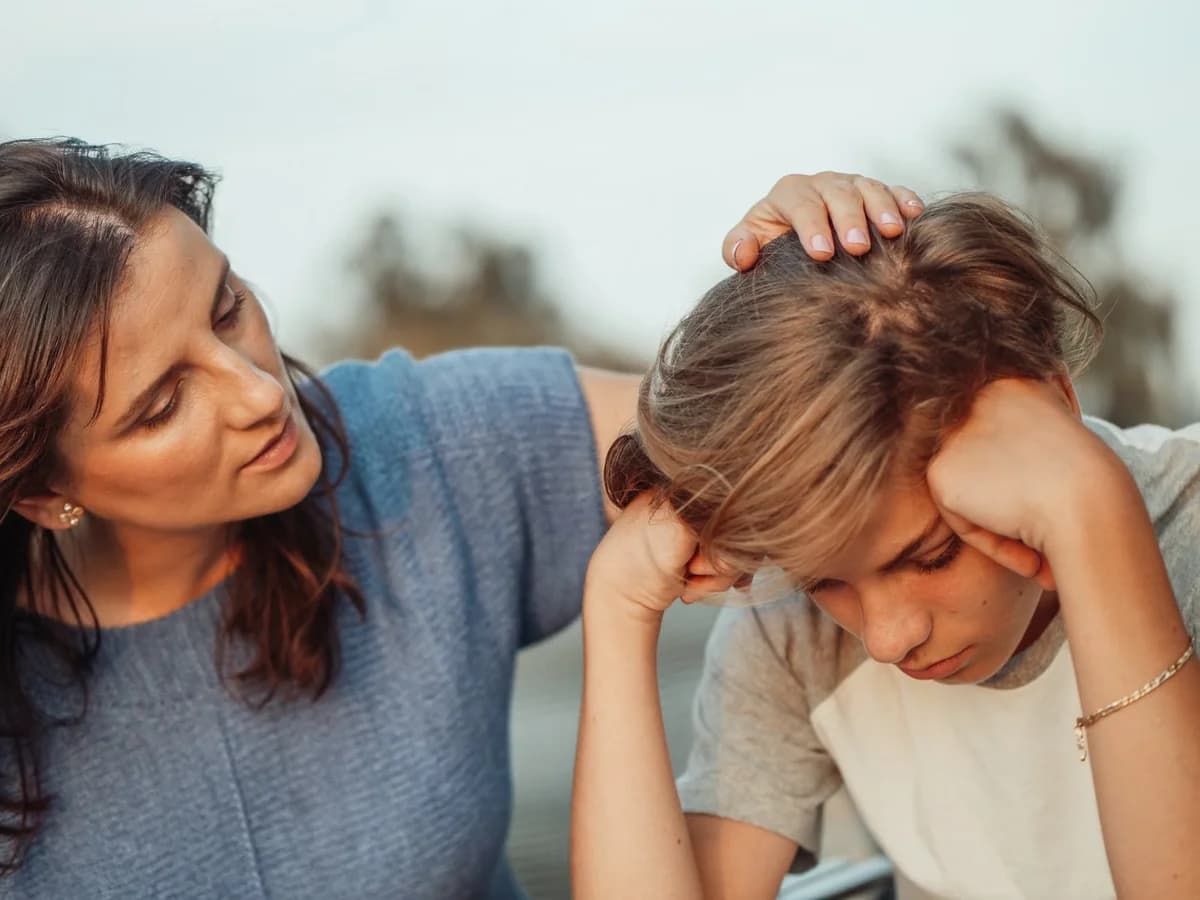 A mother comforts her upset teenage child outdoors.