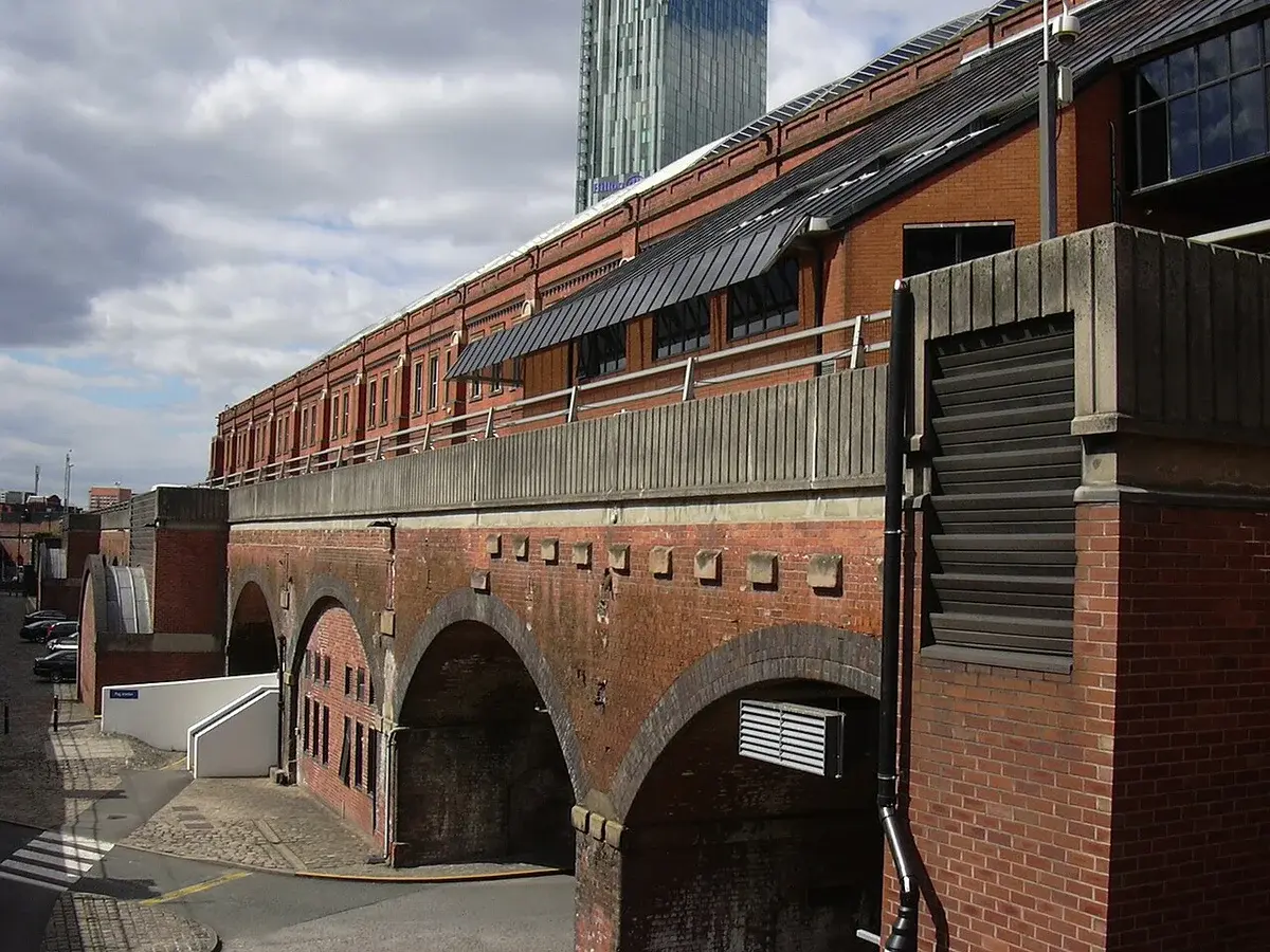 Exterior view of Manchester Central in Manchester with brick arches and a modern tower behind it.