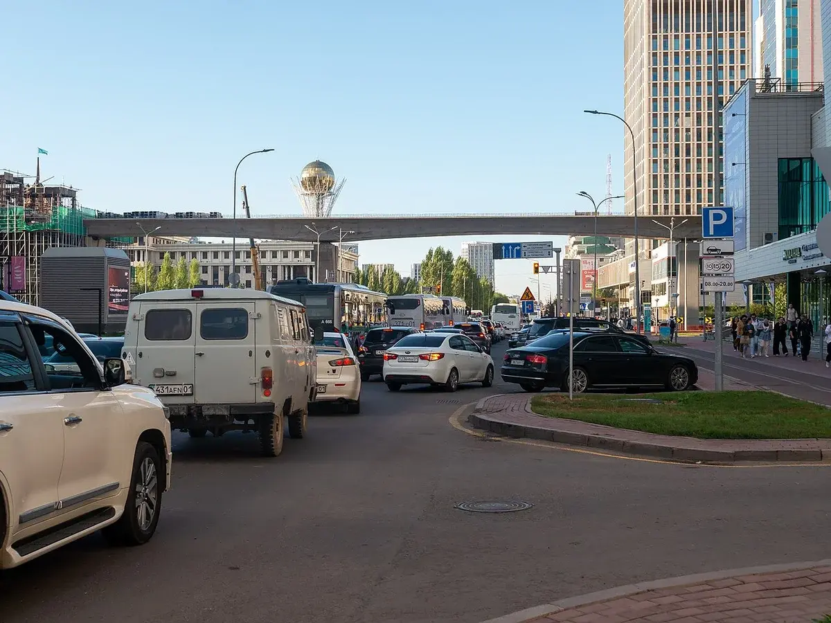 Traffic on a city street near Abu Dhabi Plaza in Astana with an elevated roadway overhead.