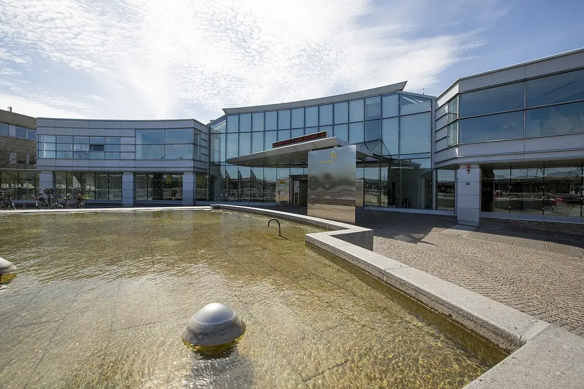 Modern glass office building with a reflecting pool in front.