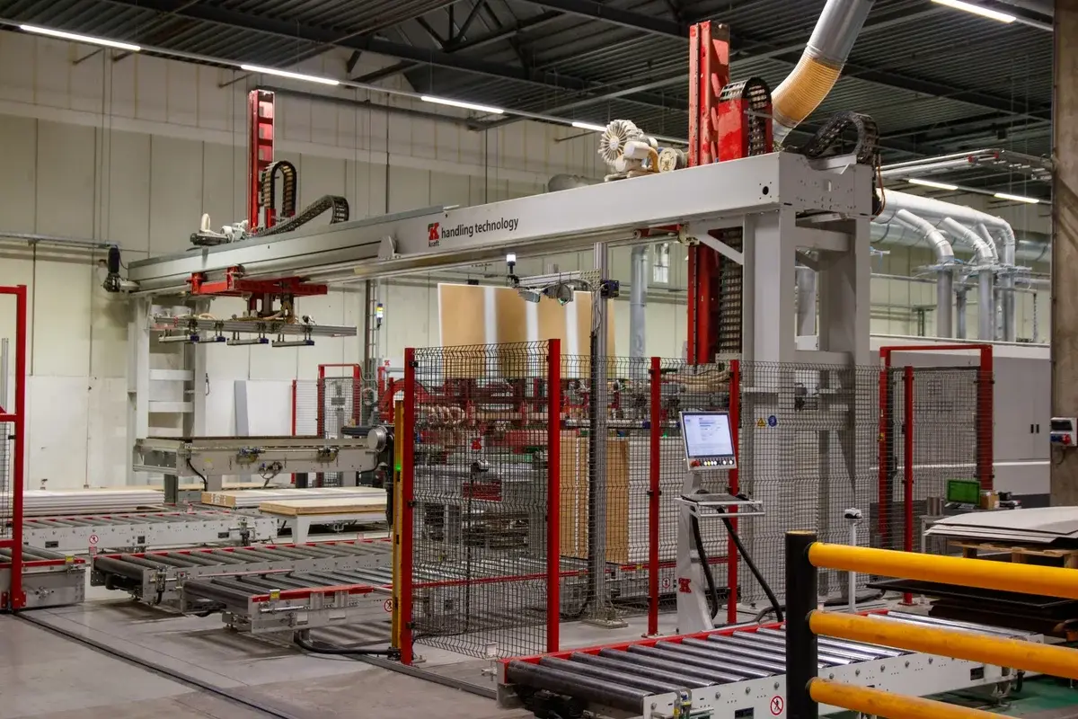 Automated machinery and conveyor systems inside a factory with safety fencing.
