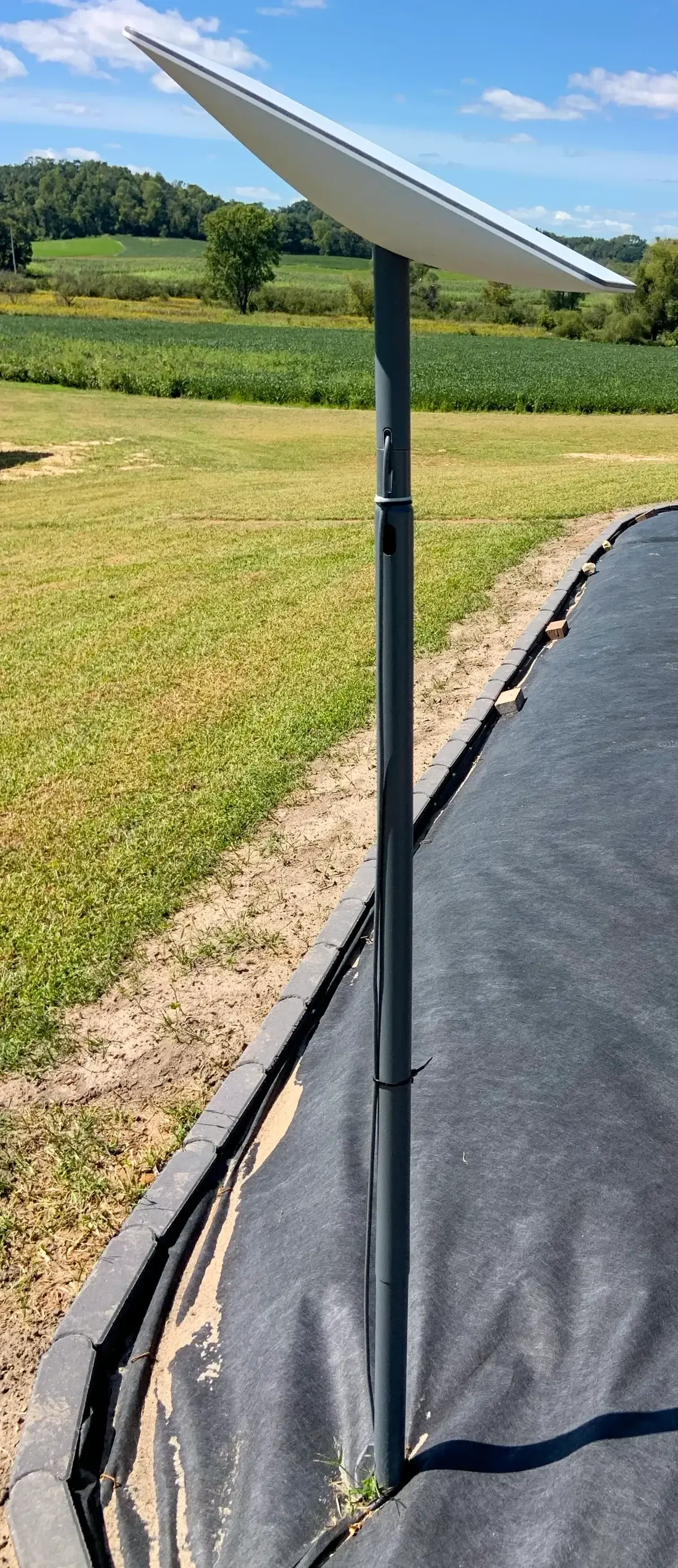 A Starlink satellite internet antenna mounted on a pole in a rural field.