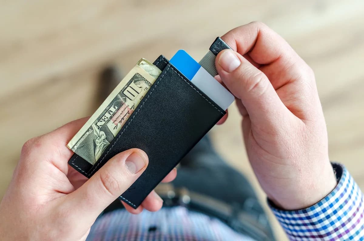 Close-up of hands holding a wallet with cash and credit cards.