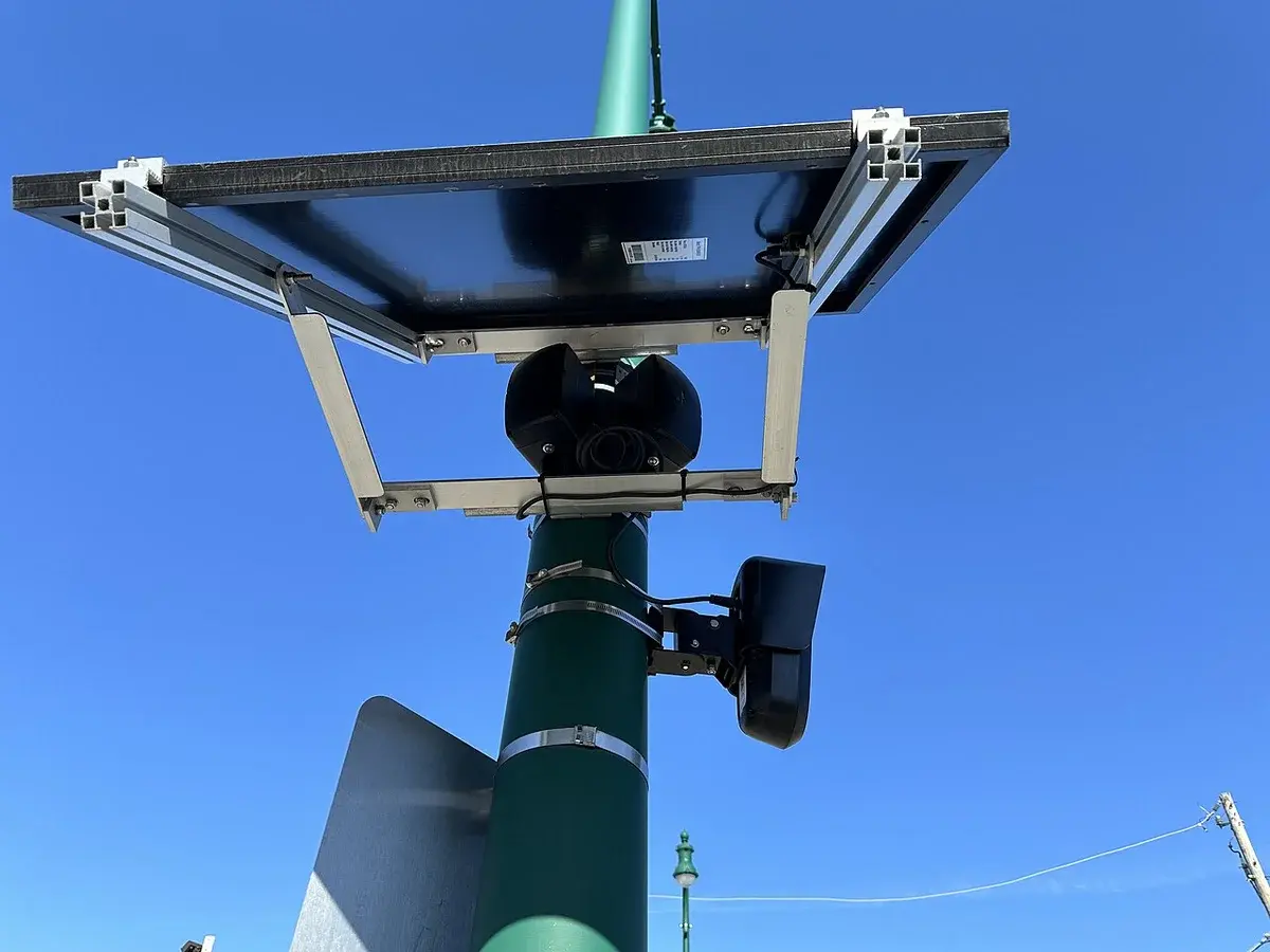 Close-up of surveillance modules mounted on a pole under a solar panel.