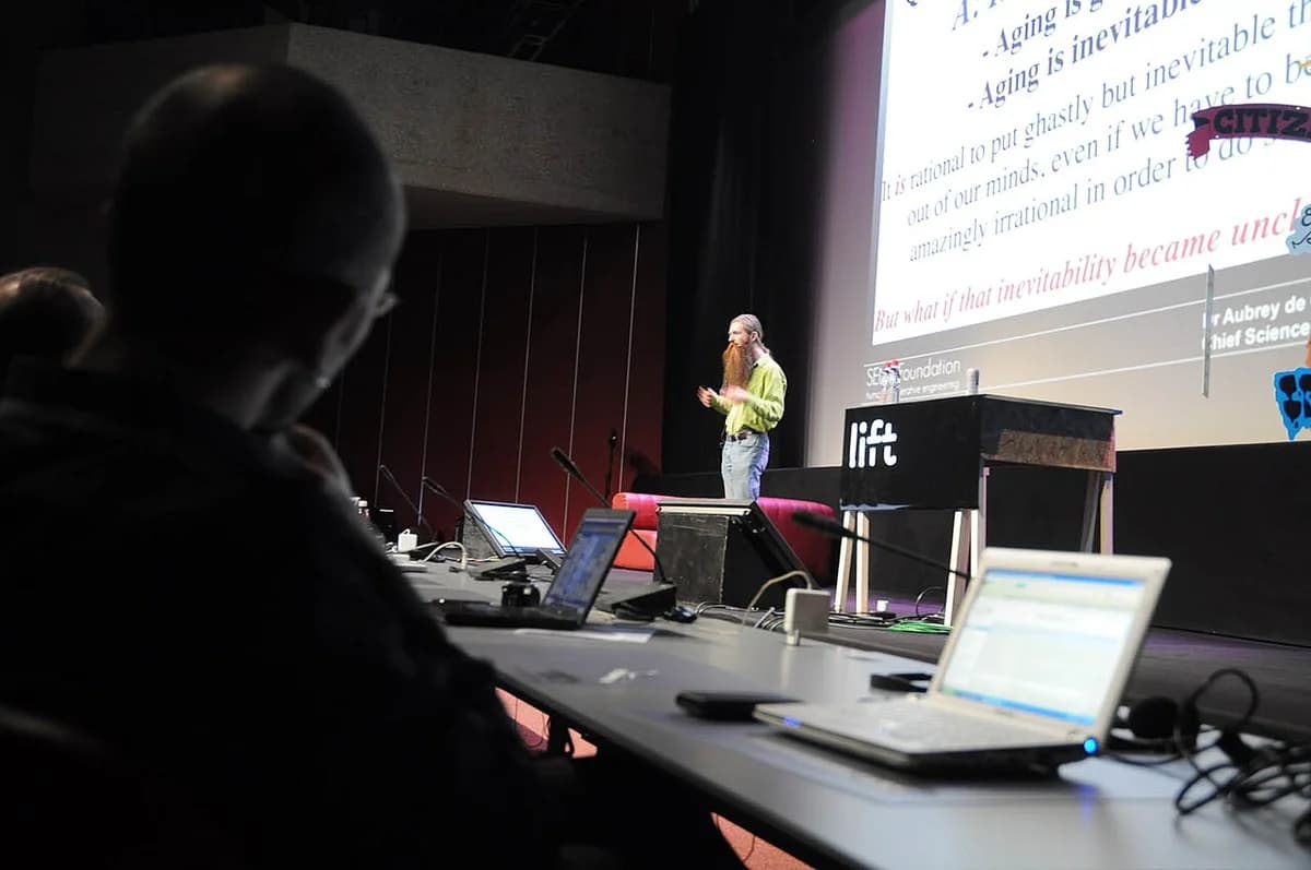 Aubrey de Grey speaking at a conference on a stage.