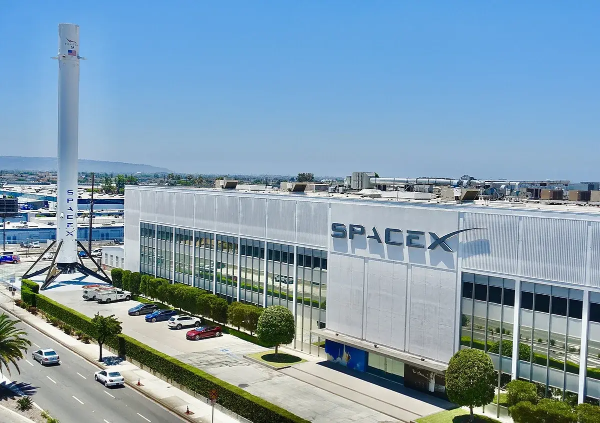SpaceX headquarters and factory in Hawthorne with a Falcon 9 booster outside.