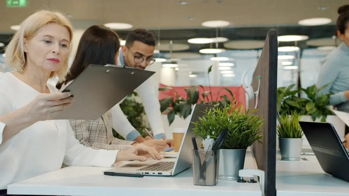 Professionals collaborating in a modern office with laptops and plants.