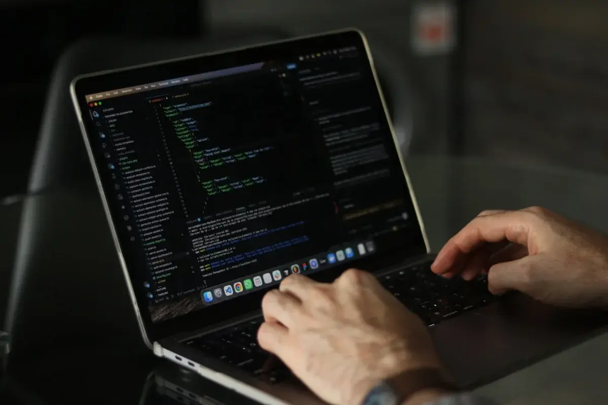 Hands typing code on a laptop.