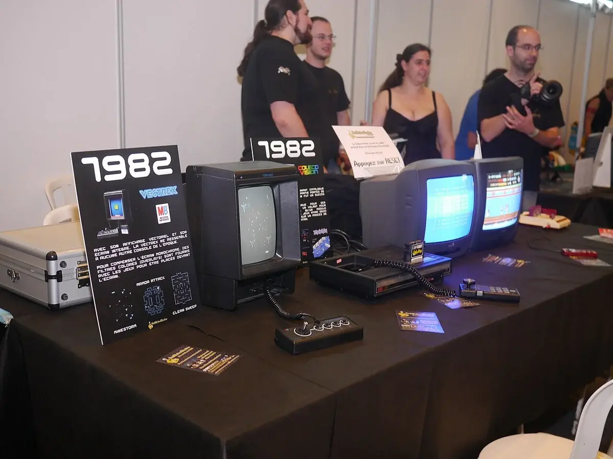 Retro gaming display with vintage consoles and CRT TVs at a festival booth.