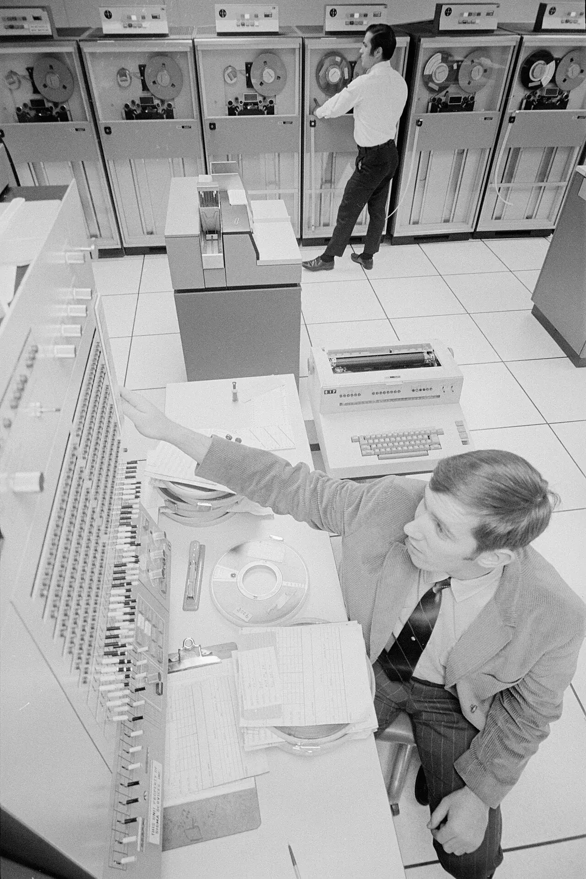 Two men operating IBM System/360 computer equipment in a computer room.