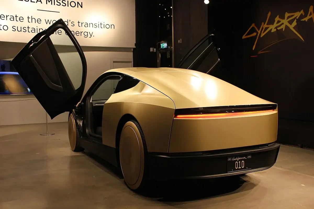 A Tesla Cybercab concept car on display indoors with its doors open.